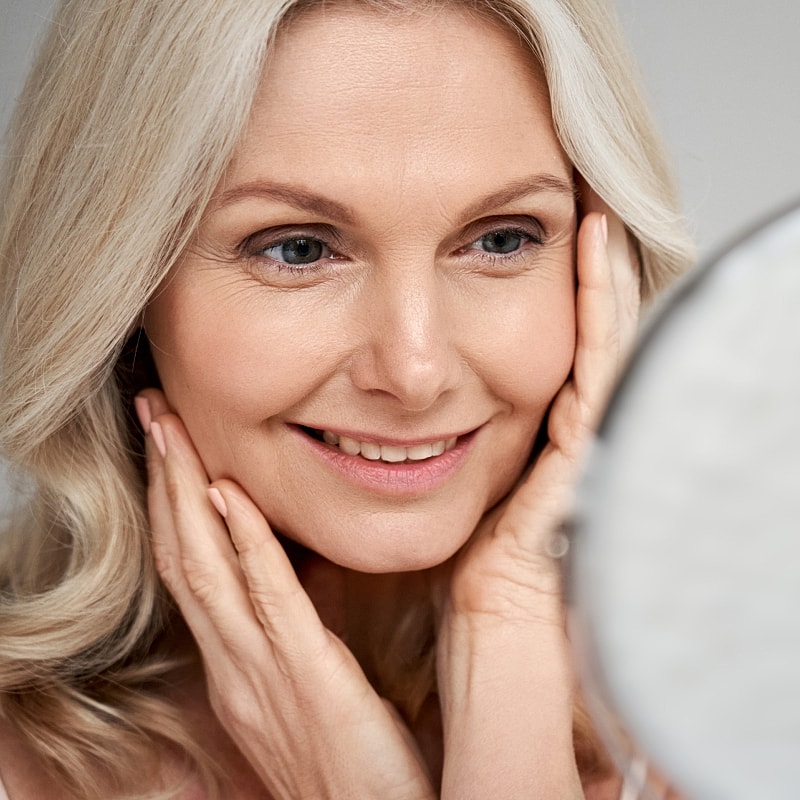 Smiling woman admiring her reflection in mirror.