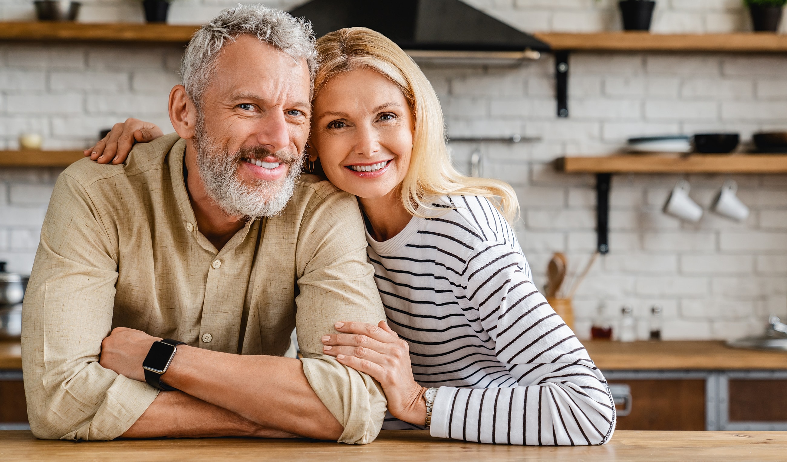 Happy couple smiling in a cozy kitchen.