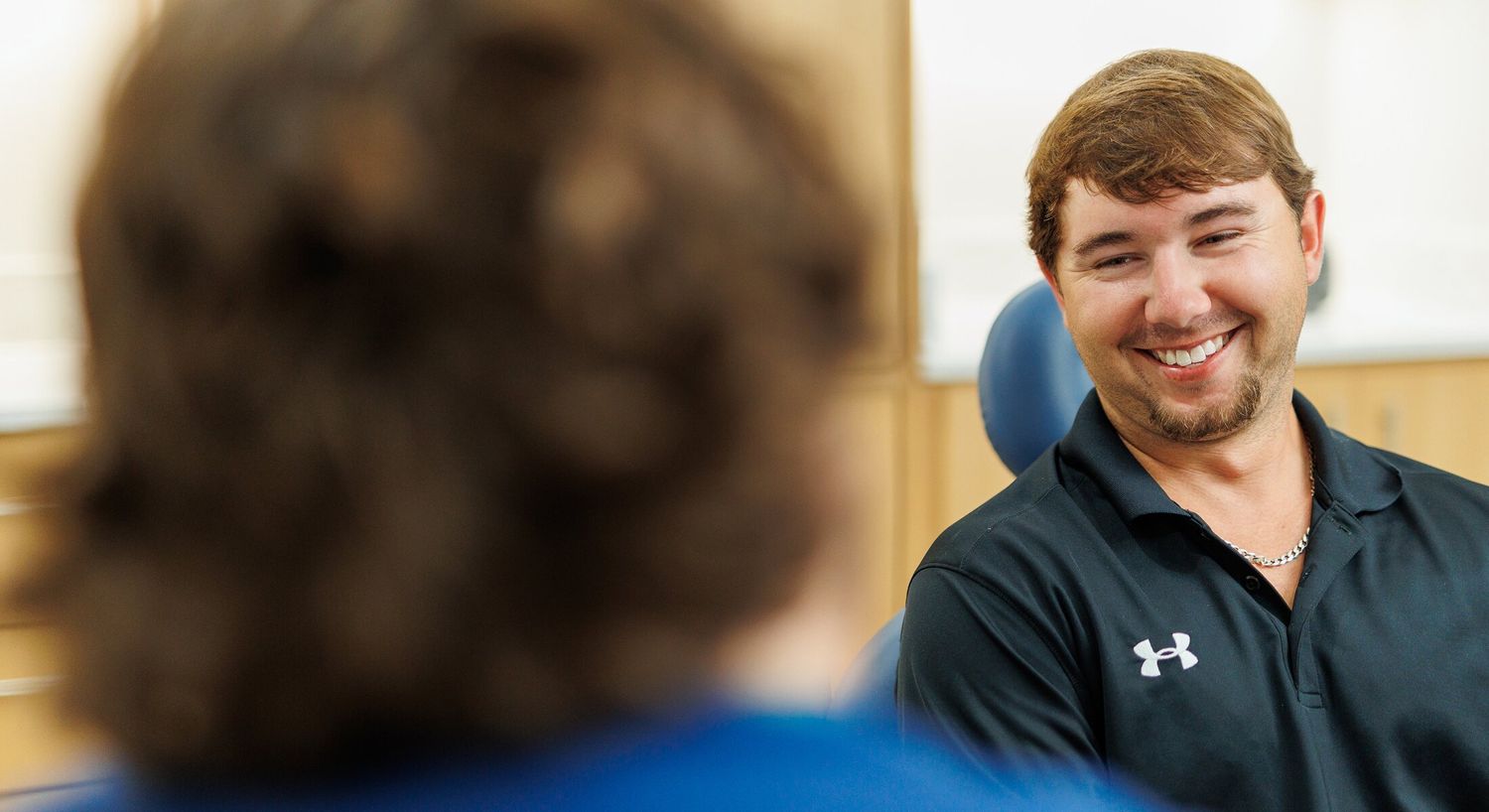 Smiling man in a dental office conversation.